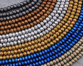 May include: Close-up of multiple strands of faceted beads in various colors, including gray, bronze, silver, gold, and blue. The beads are arranged in a circular pattern, showcasing their reflective surfaces and diverse hues. Ideal for jewelry making.
