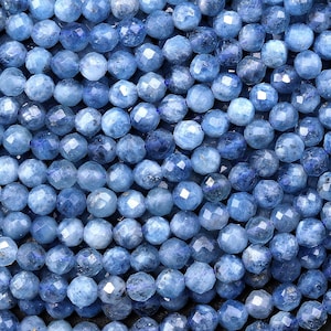 May include: A strand of light blue faceted gemstone beads. The beads are round and have a smooth, polished finish.