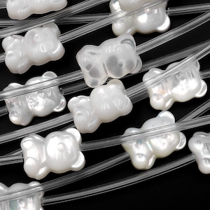 May include: White pearl-like bear-shaped beads strung on clear plastic string. The beads have a slightly iridescent finish.