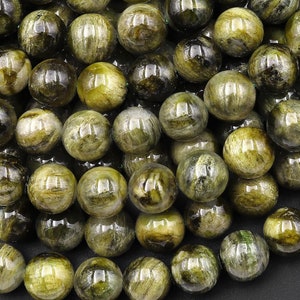 May include: A strand of round, green and gold gemstone beads. The beads are smooth and polished, with a slight shimmer.