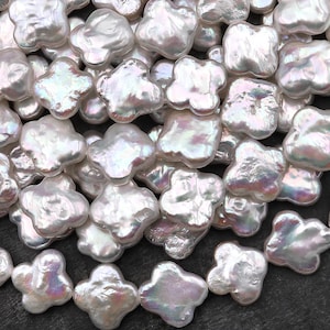 May include: A close-up shot of a collection of white, irregularly shaped pearls. The pearls have a lustrous, iridescent sheen, reflecting hints of pink, blue, and green. The overall texture is smooth and organic, with a slightly bumpy surface. These pearls are ideal for jewelry making.