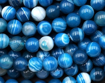 May include: A close-up of a strand of blue agate beads with white stripes. The beads are round and smooth, and they are arranged in a random pattern.