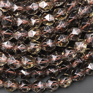 May include: A strand of faceted smoky quartz beads. The beads are a light brown color and have a faceted, starburst design. The beads are strung on a clear elastic cord.