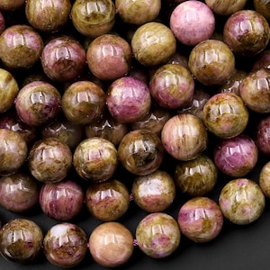 May include: A strand of round, green and pink gemstone beads. The beads have a mottled, marbled appearance.