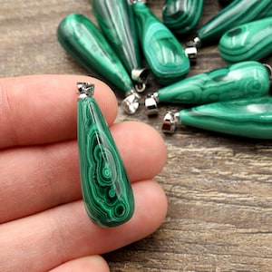 Op de afbeelding: Een verzameling groene malachiet edelsteen hangers met een zilveren beugel. De hangers zijn traanvormig en hebben een draaiende patroon.