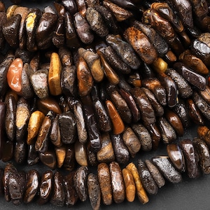May include: A strand of brown and black gemstone beads. The beads are irregularly shaped and have a smooth, polished finish.