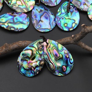 May include: A collection of iridescent abalone shell pendants in a teardrop shape. The shells have a variety of colors, including blue, green, purple, and gold. The pendants are strung on brown cords.