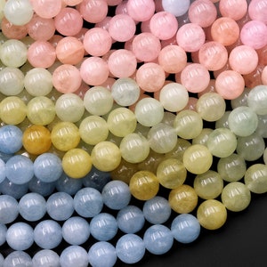 May include: A collection of round, smooth, gemstone beads in shades of blue, green, yellow, and pink. The beads are arranged in a gradient pattern, with the lightest colours at the top and the darkest colours at the bottom.