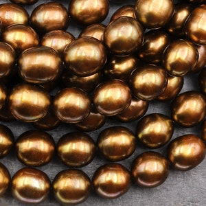 May include: A strand of brown freshwater pearls. The pearls are round and have a smooth, iridescent finish.