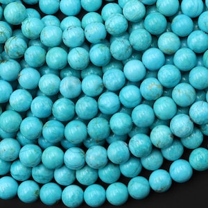 May include: A close-up shot of numerous turquoise-colored, round beads. The beads have a smooth, polished surface with natural variations in color and texture. These beads are ideal for jewelry making and crafting projects.