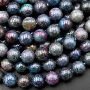 May include: A strand of round, blue-green gemstone beads with flecks of pink and green. The beads are smooth and polished.