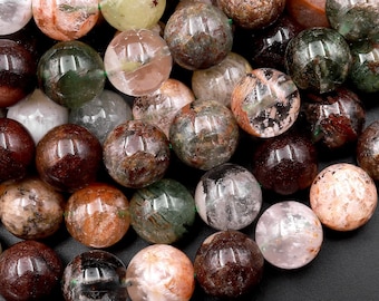 May include: A strand of round, multi-colored gemstone beads. The beads are a mix of green, brown, and clear with inclusions. The beads are approximately 10mm in diameter.