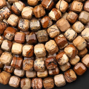 Puede incluir: Primer plano de una colección de cuentas de piedras preciosas en varios tonos de marrón, beige y crema. Las cuentas están facetadas, con múltiples superficies cortadas que crean un efecto texturizado. Las cuentas son cuadradas o rectangulares y parecen estar ensartadas.