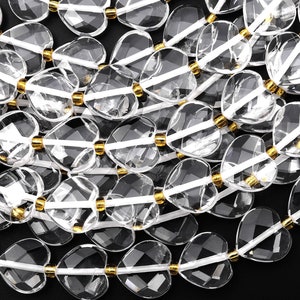 Könnte beinhalten: Eine Kette aus klaren Quarz-Herzperlen mit goldfarbenen Zwischenstücken. Die Perlen sind facettiert und haben eine durchscheinende Optik.