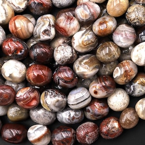 May include: A collection of tumbled agate stones in various shades of brown, red, and white. The stones are smooth and polished, with intricate patterns of banding and swirls.