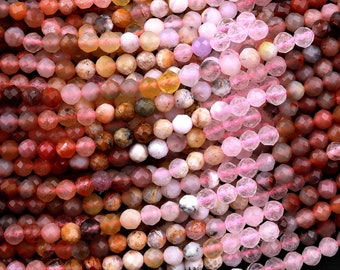 May include: A close-up of a strand of faceted gemstone beads in various shades of pink, red, and brown. The beads are all approximately 6mm in size and have a smooth, polished finish.