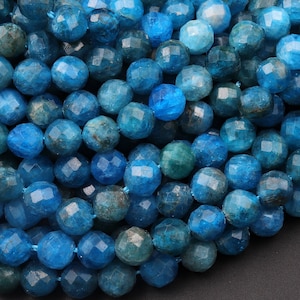 May include: A strand of blue apatite beads, faceted and polished, with a slightly cloudy appearance. The beads are round and have a smooth, glossy finish.