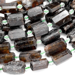 以下が含まれることがあります： 面取りされたクリスタルスペーサーが付いた、濃い茶色と黒のトルマリンビーズのストランド。ビーズは面取りされており、自然で粗い質感があります。