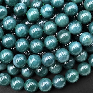May include: A strand of round, teal green jade beads. The beads are smooth and polished, with a slight sheen.