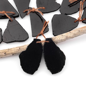 Peut inclure: Un ensemble d'étiquettes en ardoise noire avec de la ficelle brune attachée. Les étiquettes ont une forme irrégulière et un aspect rustique et naturel.