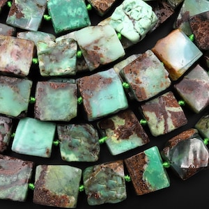 Può includere: Una collana di perle di crisoprasio verde e marrone. Le perle sono di forma quadrata e hanno una texture naturale e ruvida.