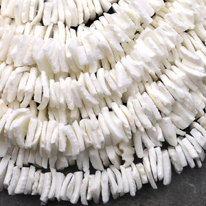 May include: A strand of white, irregular shaped, flat, shell beads. The beads are strung together with a thin, white thread.