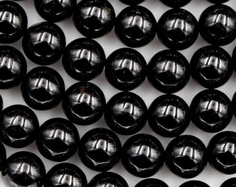 Könnte beinhalten: Eine Schnur aus schwarzen Onyx-Perlen, jede Perle ist rund und glatt. Die Perlen sind in einem Kreis angeordnet, wobei sich die Ränder des Kreises leicht überlappen.
