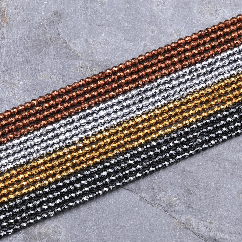May include: A strand of faceted gemstone beads in four colors: copper, silver, gold, and black. The beads are arranged in rows, with each row a different color.