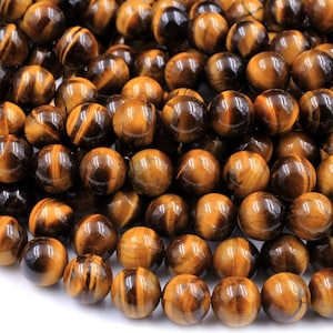 May include: A strand of round, polished tiger's eye beads in shades of brown and gold. The beads have a natural, striated pattern and a glossy finish.