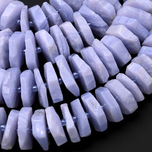 May include: A strand of blue lace agate gemstone beads. The beads are faceted and have a natural, irregular shape. They are strung on a clear elastic cord.