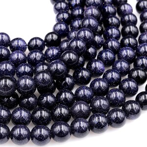 Op de afbeelding: Een streng donkerblauwe ronde edelsteen kralen met een gespikkelde textuur. De kralen zijn glad en gepolijst.