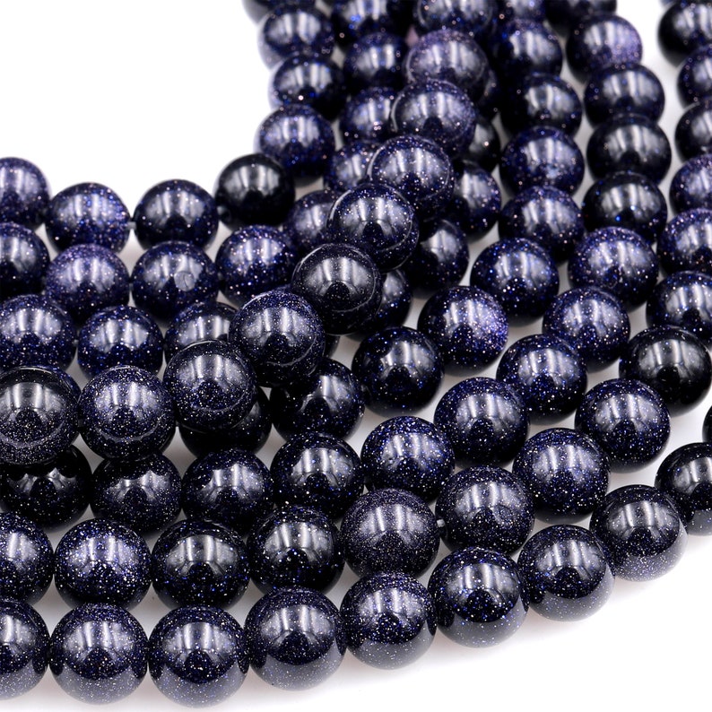 Op de afbeelding: Een streng donkerblauwe ronde edelsteen kralen met een gespikkelde textuur. De kralen zijn glad en gepolijst.