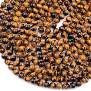May include: A strand of round, polished tiger's eye beads. The beads are a mix of golden brown and black colors with a shimmering, iridescent effect.