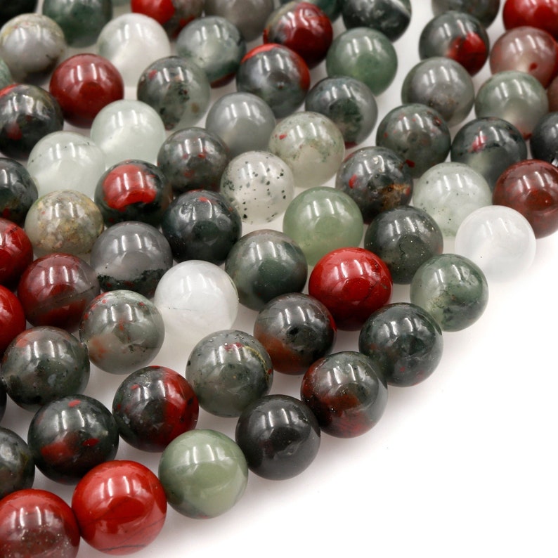 May include: A strand of round, green, red, and white gemstone beads. The beads are smooth and polished, and they have a natural, organic look.