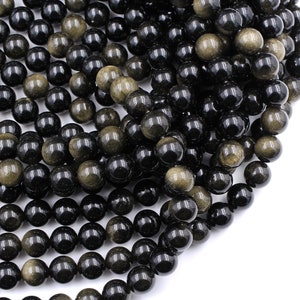 May include: A strand of black and gold gemstone beads. The beads are round and have a smooth, polished finish.