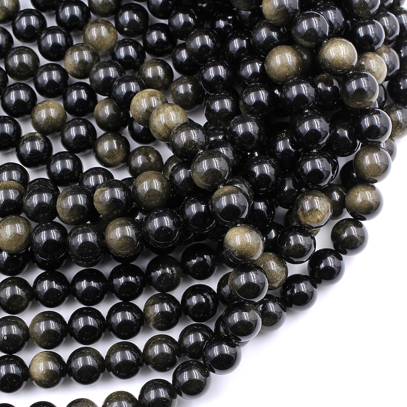 May include: A strand of black and gold gemstone beads. The beads are round and have a smooth, polished finish.
