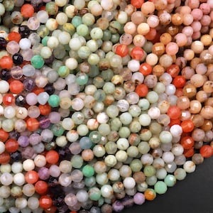 May include: A close-up of a variety of faceted gemstone beads in shades of green, orange, pink, and purple. The beads are arranged in a random pattern, creating a colorful and textured background.