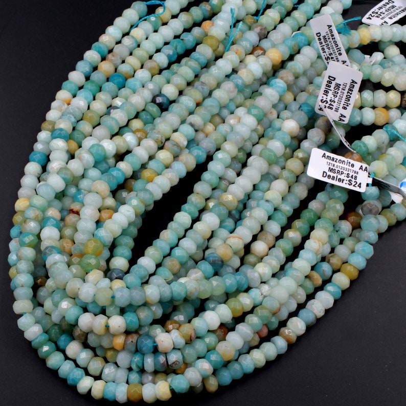 K&ouml;nnte beinhalten: Eine Schnur facettierter Amazonit-Perlen, etwa 4 mm gro&szlig;, in gr&uuml;n-blauer Farbe. Die Perlen sind auf einem Faden aufgef&auml;delt und bereit f&uuml;r die Schmuckherstellung. Das Bild enth&auml;lt ein Preisschild mit dem Text "Amazonite AA 1218.0120331788 MSRP:$48 Dealer:$24".