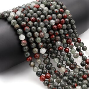 May include: A strand of round, green, red, and white gemstone beads. The beads are approximately 6mm in diameter and have a speckled, marbled appearance.