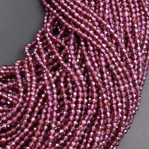 Puede incluir: Una hebra de cuentas de piedras preciosas facetadas de color rojo intenso. Las cuentas son pequeñas y redondas, con un acabado brillante y pulido.