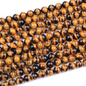 May include: A strand of round, golden brown tiger's eye beads. The beads have a shimmering, chatoyant effect.