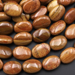 May include: A collection of polished, oval-shaped stones in shades of brown, tan, and reddish-brown. The stones have a smooth, glossy surface with natural patterns and variations in color, creating a unique and earthy appearance. These stones are ideal for jewelry making or decorative purposes.