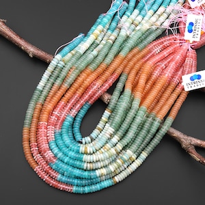 May include: A collection of gemstone bead strands in turquoise, coral, orange, and green hues. The flat, disc-shaped beads are strung together, creating a textured, layered effect. The beads are displayed on a dark surface.