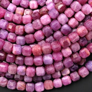 Könnte beinhalten: Eine Strähne aus rosa und violetten Edelsteinperlen. Die Perlen sind facettiert und haben eine quadratische Form.