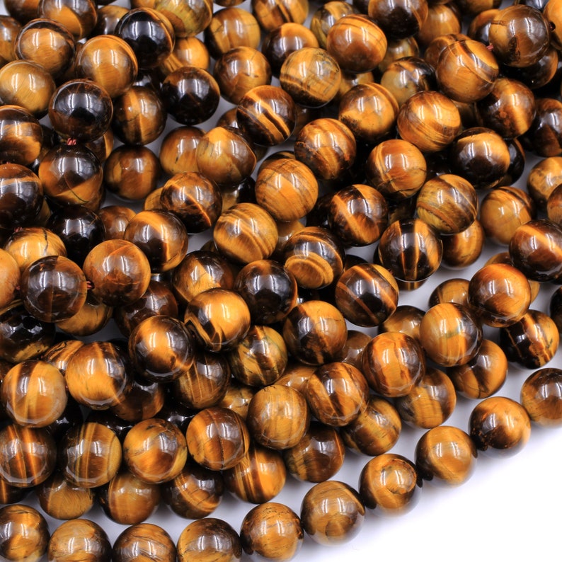 May include: A strand of round, polished tiger's eye beads in shades of brown and gold. The beads have a natural, striated pattern and a glossy finish.