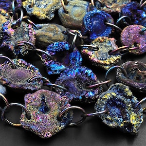 Könnte beinhalten: Nahaufnahme einer Halskette aus schillernden, facettierten, blauen, violetten und goldenen Edelsteinperlen. Die Perlen sind durch silberne Metallringe verbunden.