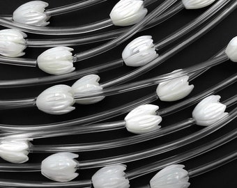 May include: A strand of white pearl-like beads strung on clear plastic cord. The beads are shaped like small flowers.