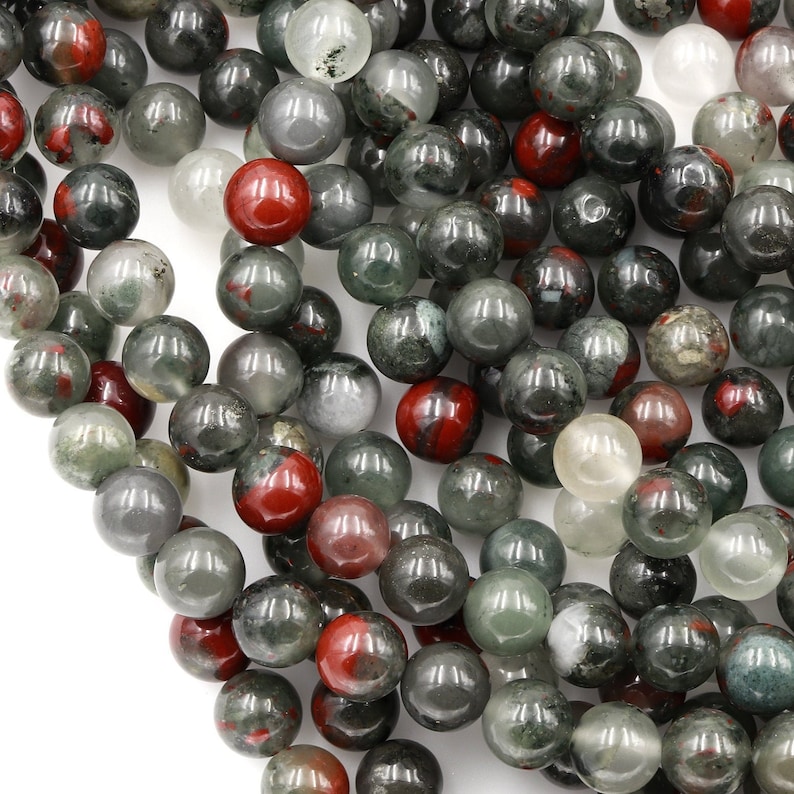 May include: A strand of round, green, red, and clear gemstone beads. The beads are approximately 8mm in diameter and have a smooth, polished finish.
