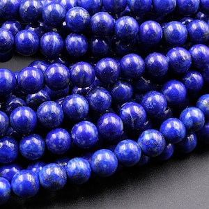 Puede incluir: Una hebra de cuentas de lapisl&aacute;zuli azul oscuro con motas de pirita dorada. Las cuentas redondas son lisas y pulidas, creando un aspecto lujoso.