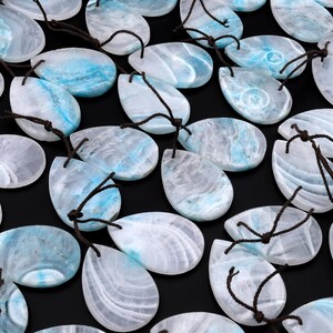 May include: A collection of teardrop-shaped pendants made of white and blue agate with brown string attached to each pendant.